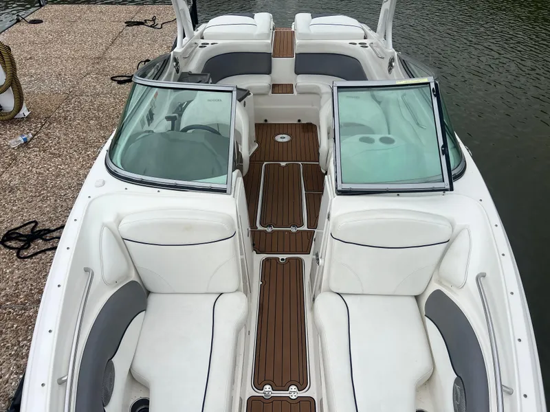 Slide: The Image of 2011 Rinker 276 Captiva Bowrider with white seating and wooden deck, docked by the water. - 28
