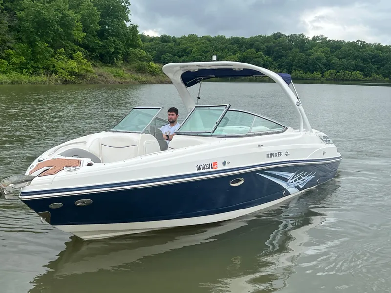 Slide: The Image of 2011 Rinker 276 Captiva Bowrider on a calm lake with lush green surroundings. - 9