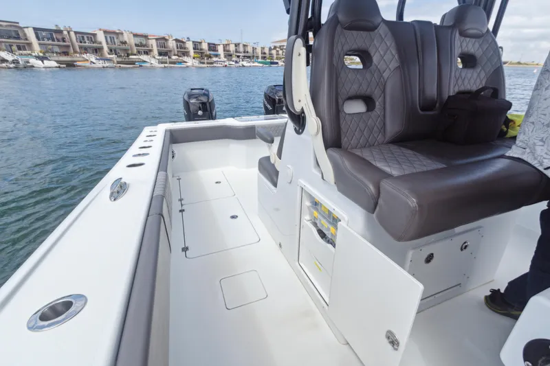 Slide: The Image of 2022 Freeman 34VH boat interior with cushioned seating and open deck, docked near waterfront homes. - 15