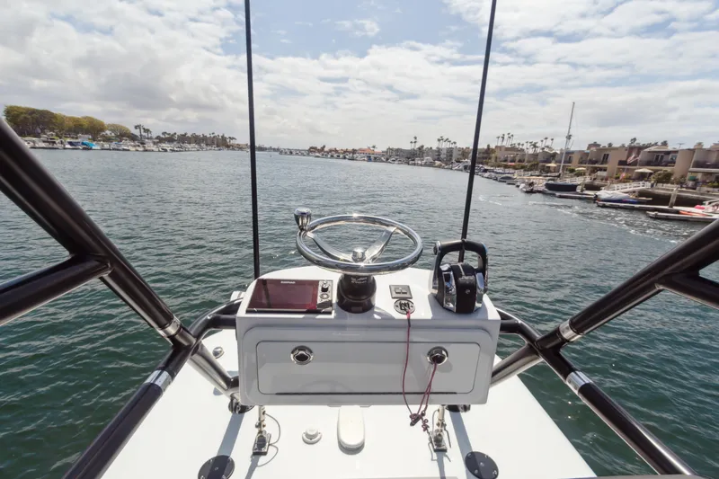 Slide: The Image of Helm view of 2022 Freeman 34VH boat navigating a scenic coastal waterway. - 7