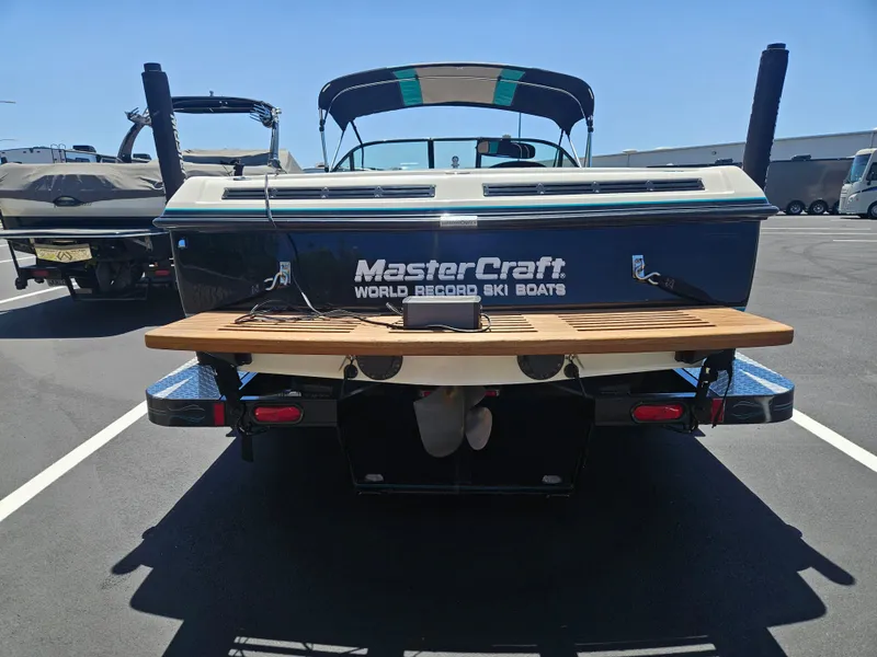 Slide: The Image of 1992 MasterCraft Prostar 205 boat, rear view, parked on asphalt, showcasing wooden swim platform. - 13