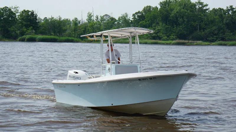 Slide: The Image of 1998 Sea Ox 20'6" boat cruising on a river with lush green trees in the background. - 6