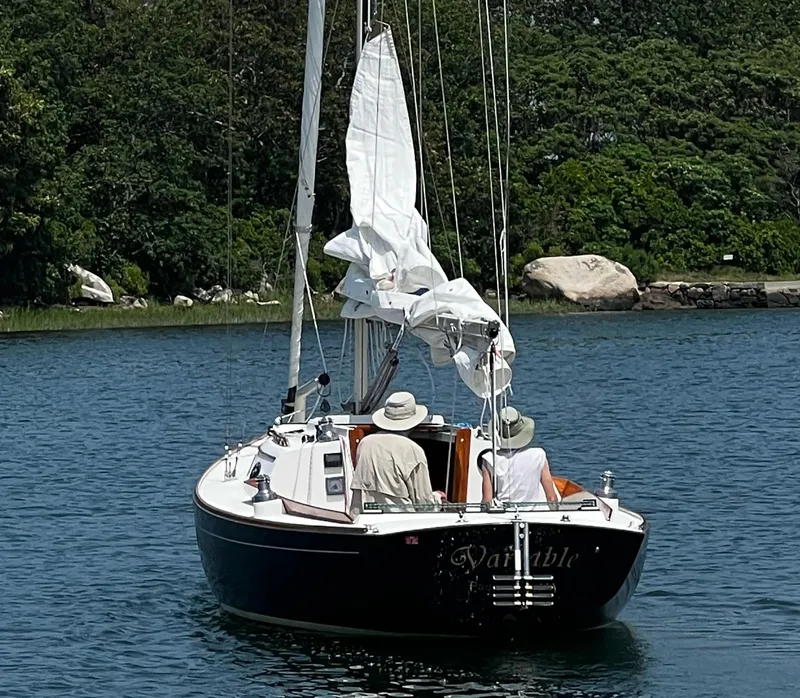 Slide: The Image of Alerion Express 28 sailboat from 1997 on calm water, with two people aboard. - 11