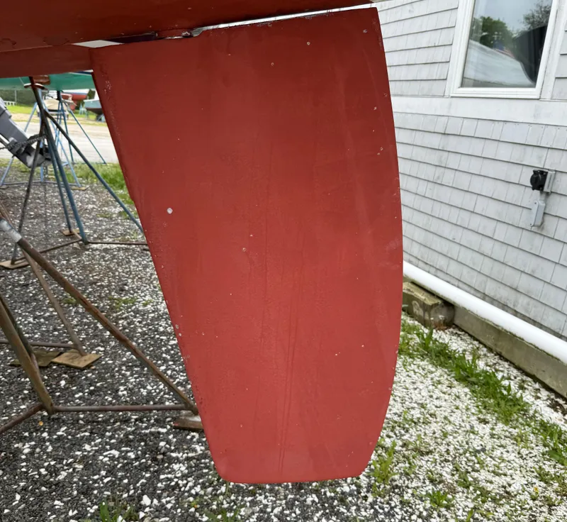 Slide: The Image of Red rudder of a 1997 Alerion Express 28 sailboat on a gravel surface. - 6