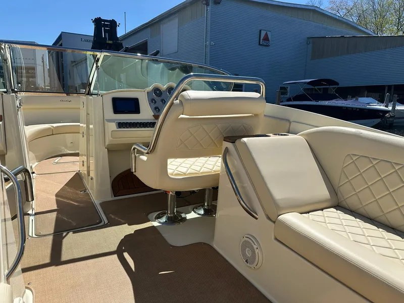 Slide: The Image of 2016 Chris-Craft Launch 28 interior with beige seating and dashboard, docked at marina. - 10