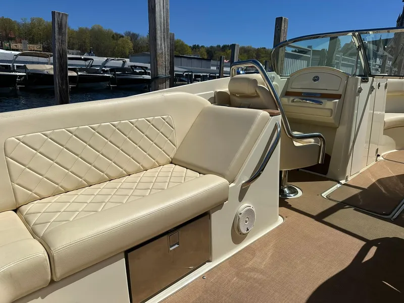 Slide: The Image of 2016 Chris-Craft Launch 28 interior with beige seating and steering area, docked by the water. - 11