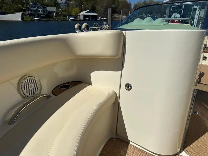 Slide: The Image of 2016 Chris-Craft Launch 28 interior with beige seating and speaker, docked by a lake. - 19