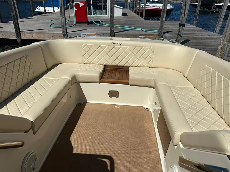 Slide: The Image of 2016 Chris-Craft Launch 28 boat interior with beige quilted seating at a dock. - 24