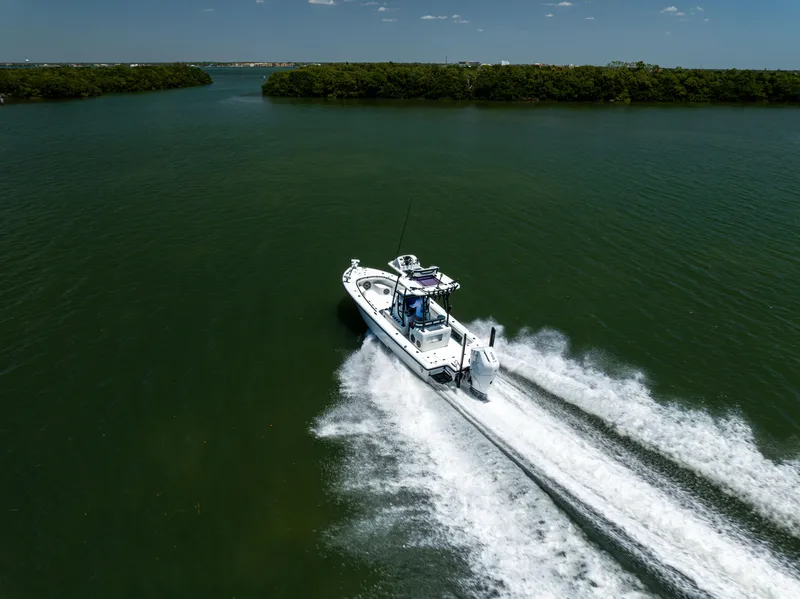 Slide: The Image of 2020 Barker Boatworks 26 speeding on open water, surrounded by lush greenery. - 8