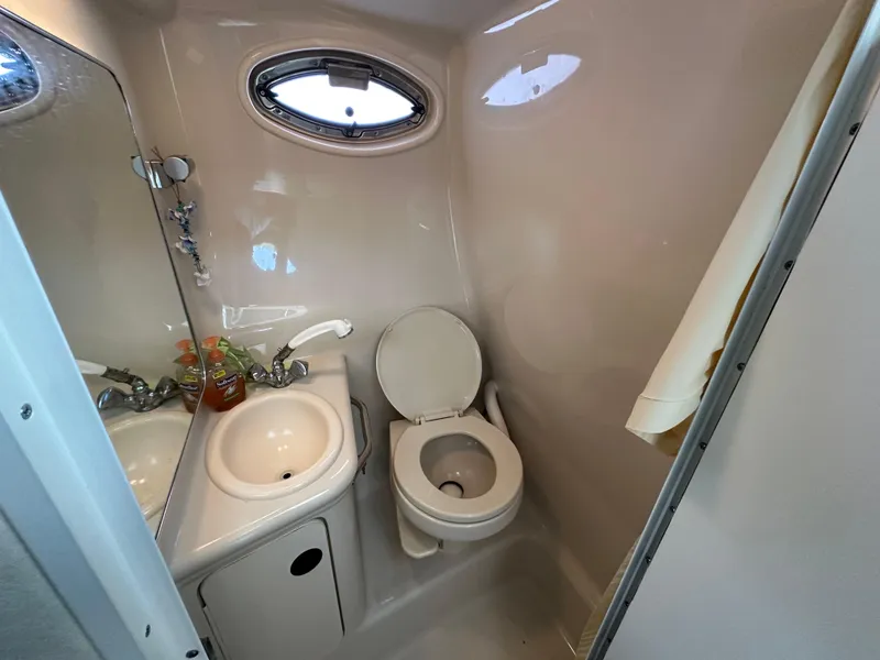 Slide: The Image of 2002 Sea Ray 240 Sundancer bathroom with sink, toilet, and porthole window. - 17