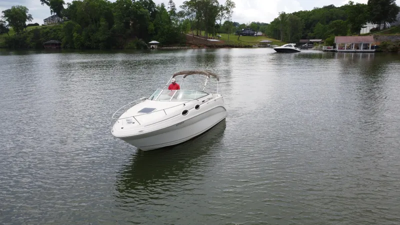 Slide: The Image of 2002 Sea Ray 240 Sundancer boat on a calm lake with trees in the background. - 2
