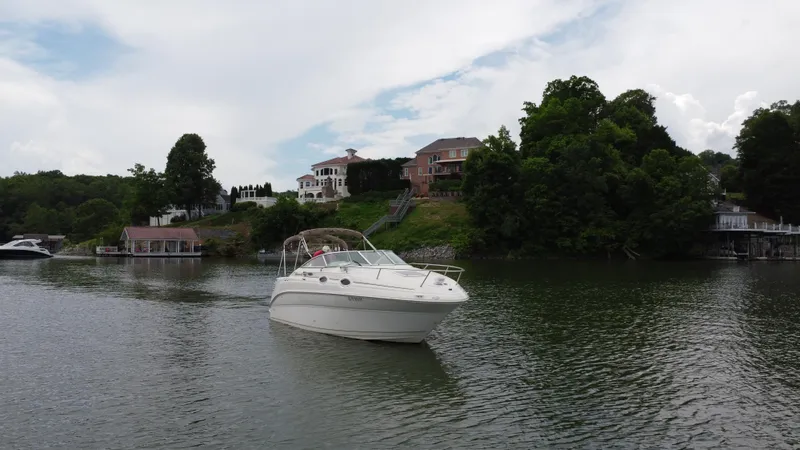 Slide: The Image of 2002 Sea Ray 240 Sundancer cruising on a scenic lake with waterfront homes. - 4