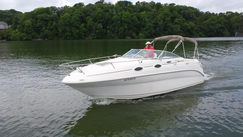 Slide: The Image of 2002 Sea Ray 240 Sundancer cruising on a serene lake with lush green trees. - 5