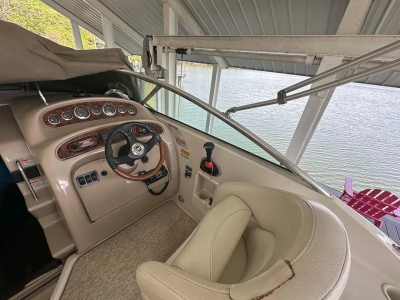 Slide: The Image of 2002 Sea Ray 240 Sundancer helm with steering wheel and gauges under a covered dock. - 7