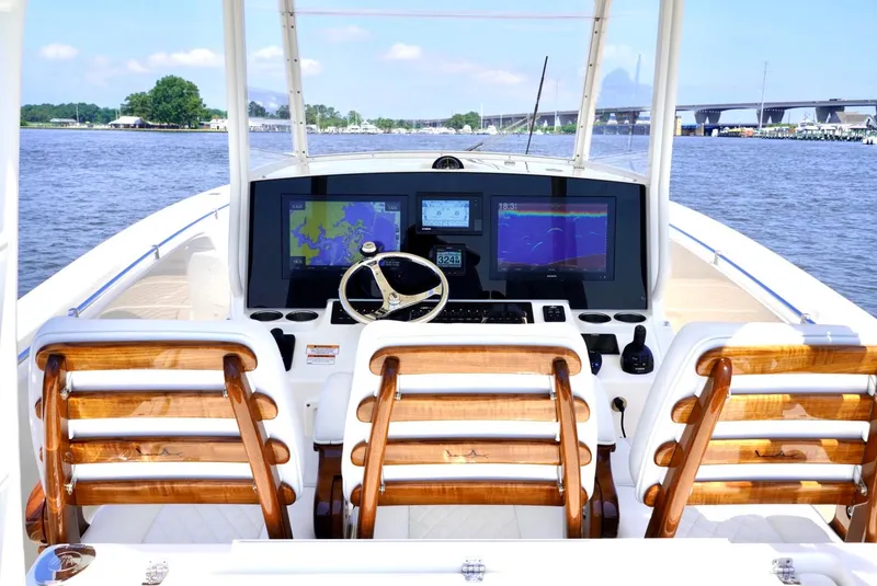 Slide: The Image of 2020 Cobia 350 Center Console boat with advanced navigation system and wooden seating on a calm waterway. - 11