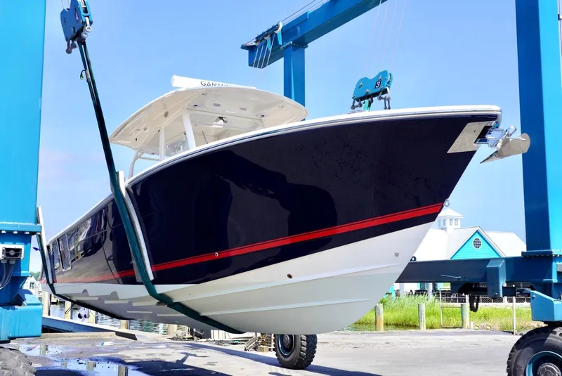Slide: The Image of 2020 Cobia 350 Center Console boat being lifted by a blue crane. - 2