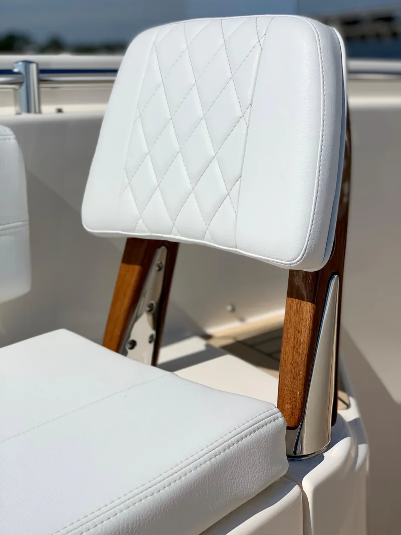 Slide: The Image of 2020 Cobia 350 Center Console boat seat with white diamond-stitched upholstery and wooden accents. - 8