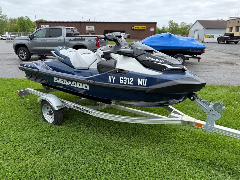 Slide: The Image of 2024 Sea-Doo GTX Limited 300 Blue Abyss on trailer, parked on grass. - 1
