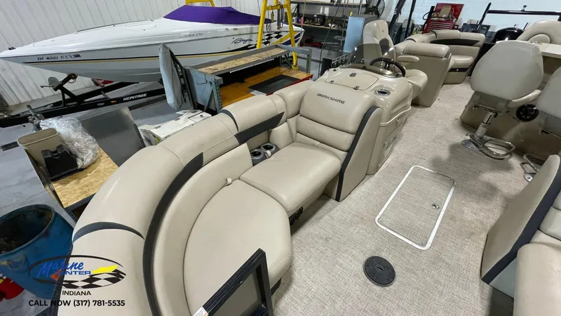 Slide: The Image of 2020 Berkshire STS Entertainment 25 pontoon boat interior with beige seating in a showroom. - 16