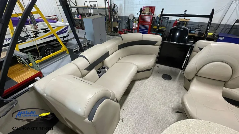 Slide: The Image of 2020 Berkshire STS Entertainment 25 pontoon boat interior with beige seating in a workshop. - 4