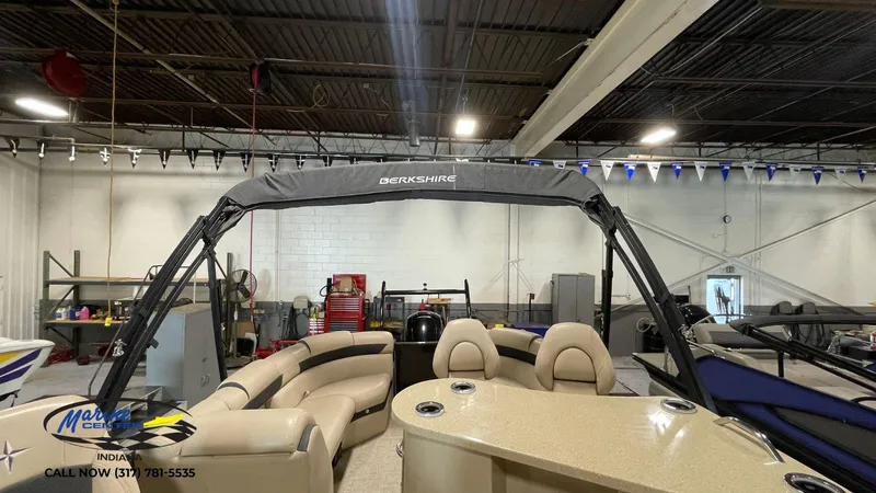 Slide: The Image of 2020 Berkshire STS Entertainment 25 pontoon boat in showroom, featuring beige seating and canopy. - 8