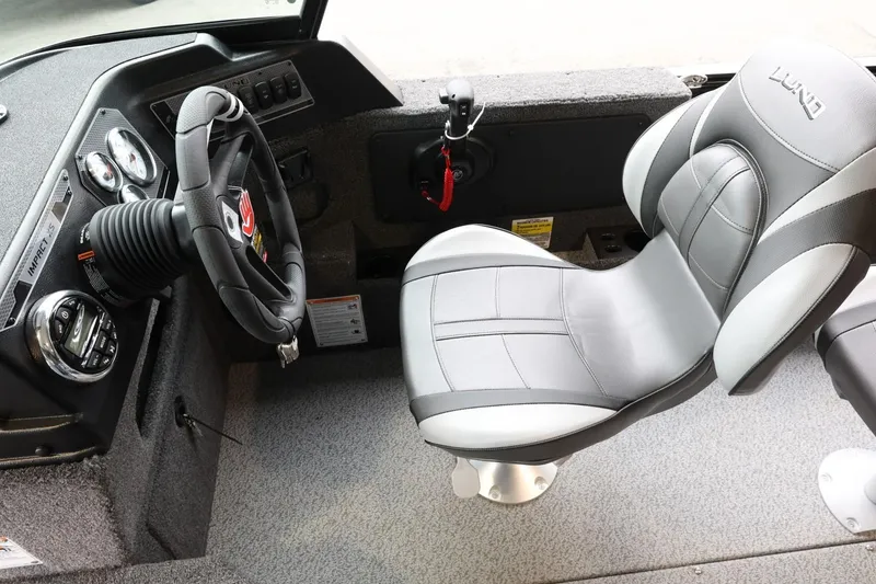 Slide: The Image of 2025 Lund 1875 Impact XS Sport boat interior with steering wheel and cushioned seat. - 17