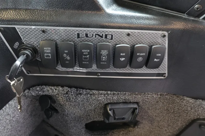 Slide: The Image of Control panel of 2025 Lund 1875 Impact XS Sport boat with various switches and key ignition. - 18