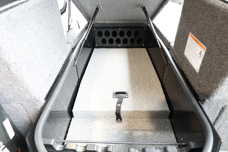 Slide: The Image of 2025 Lund 1875 Impact XS Sport boat storage compartment, open lid, carpeted interior. - 25