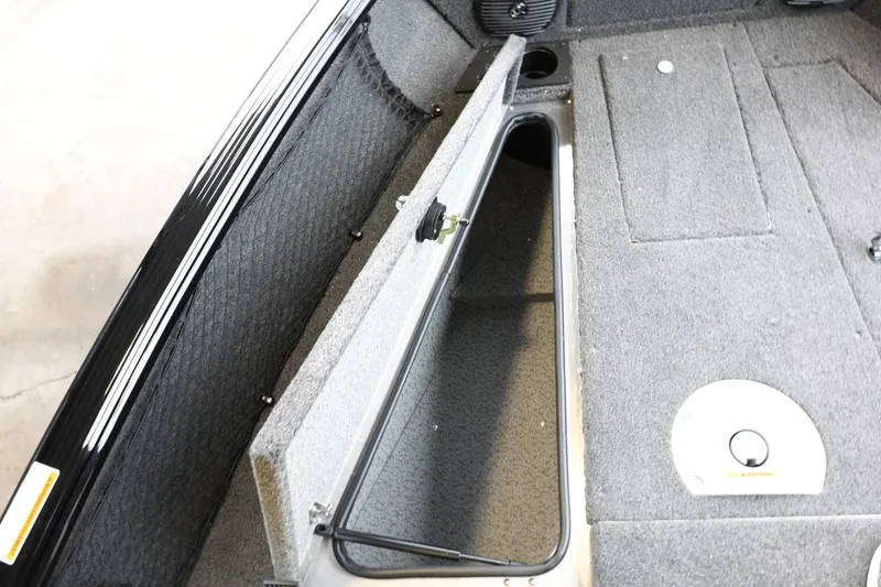 Slide: The Image of 2025 Lund 1875 Impact XS Sport boat interior storage compartment, open and carpeted. - 30