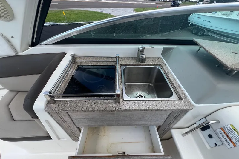 Slide: The Image of 2014 Sea Ray 260 Sundancer cockpit with helm, seating, and kitchenette area. - 21