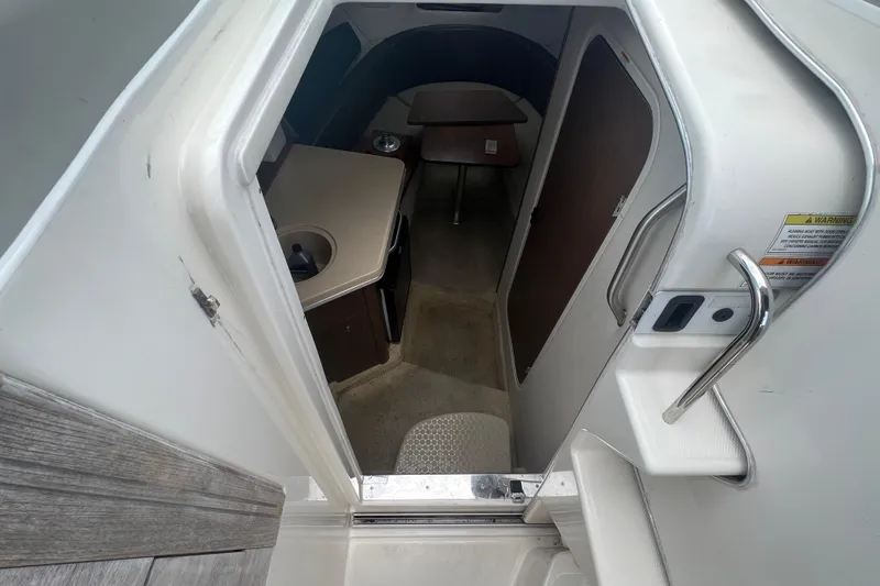 Slide: The Image of 2014 Sea Ray 260 Sundancer cabin interior with beige seating and wood accents. - 27