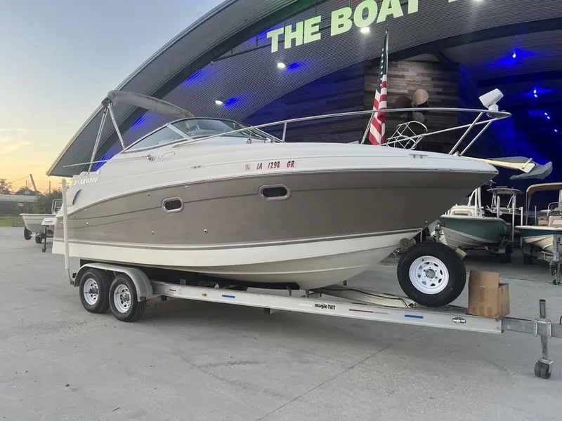 Slide: The Image of 2004 Four Winns 248 Vista boat on trailer, parked outside a showroom at sunset. - 1