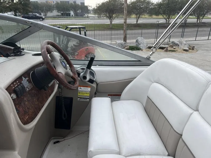 Slide: The Image of 2004 Four Winns 248 Vista boat interior with white seating and wood-accented steering area. - 8