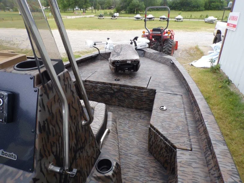 Slide: The Image of 2025 Xpress H20BAY boat with camouflage design, parked near a tractor. - 9