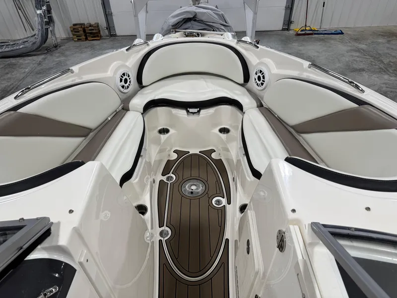 Slide: The Image of 2012 Larson LXi 288 boat interior with white and brown seating in a garage. - 12