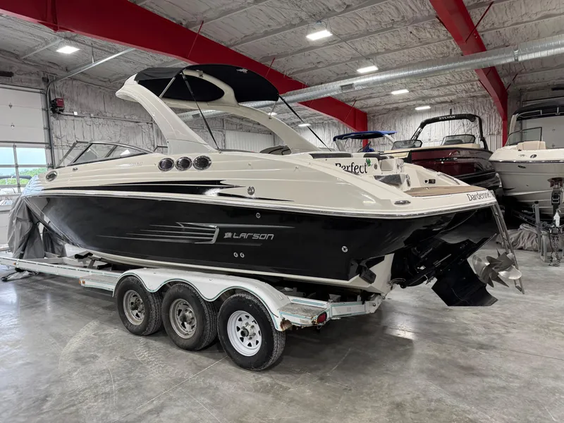 Slide: The Image of 2012 Larson LXi 288 boat on a trailer in a spacious indoor storage facility. - 4