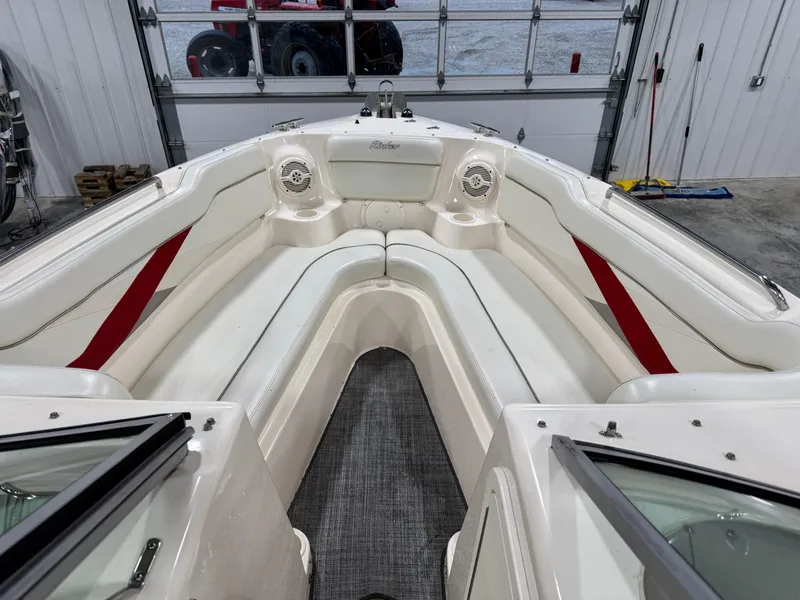 Slide: The Image of 2005 Rinker 282 BR boat interior with white seating and red accents in a garage. - 10