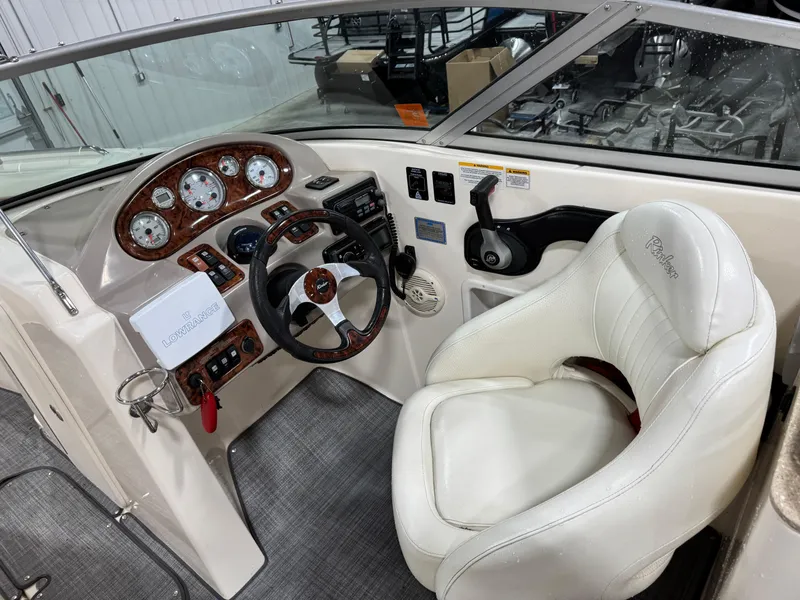 Slide: The Image of 2005 Rinker 282 BR boat cockpit with white leather seat and wood-accented dashboard. - 12