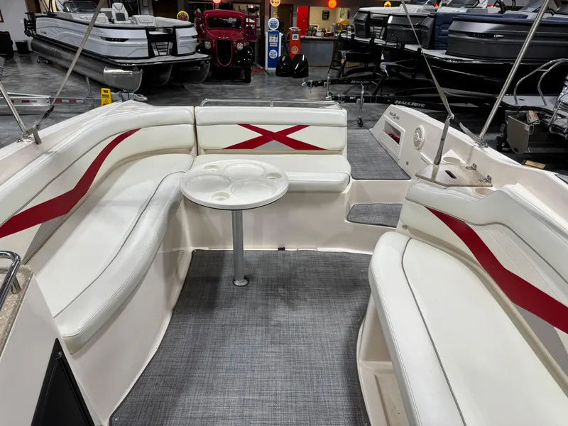 Slide: The Image of 2005 Rinker 282 BR boat interior with white and red seating, small table, and carpeted floor. - 15