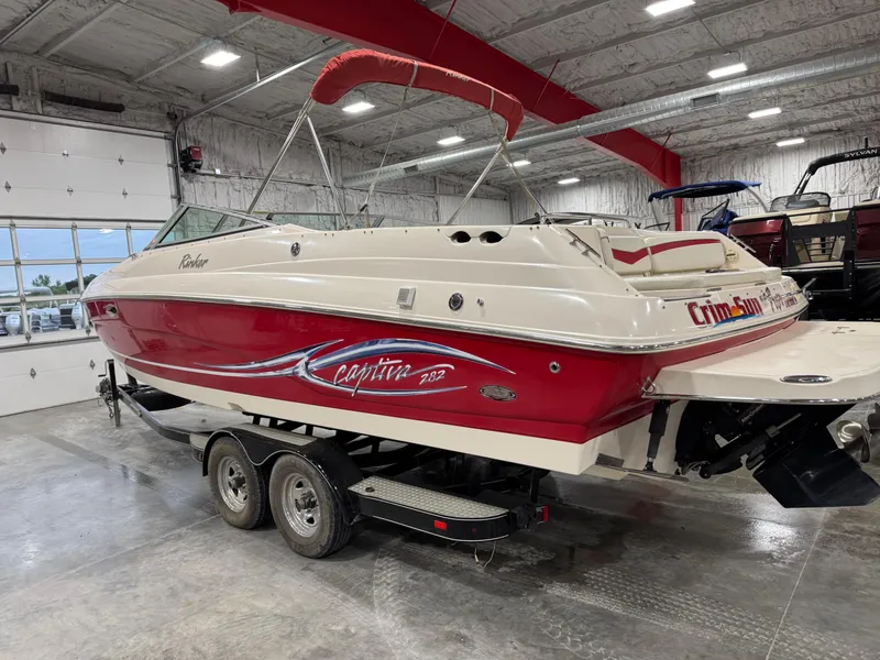 Slide: The Image of 2005 Rinker 282 BR boat with red and white design in a showroom on a trailer. - 3