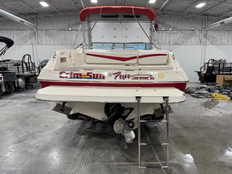 Slide: The Image of 2005 Rinker 282 BR boat in a warehouse, featuring a swim platform and ladder. - 6