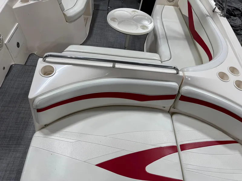 Slide: The Image of 2005 Rinker 282 BR boat interior with white and red seating, cup holders, and table. - 8
