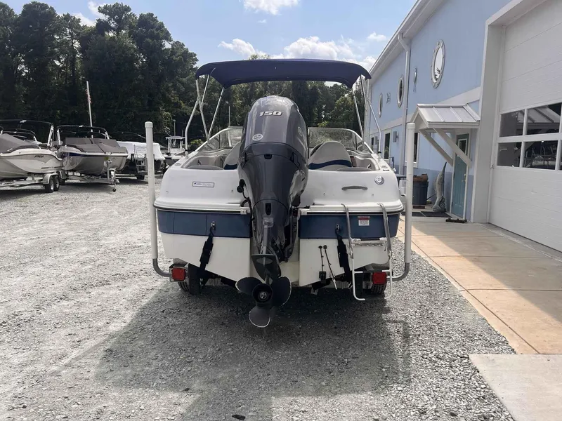 Slide: The Image of 2000 Four Winns 180 Horizon boat with outboard motor, parked near a blue building. - 3
