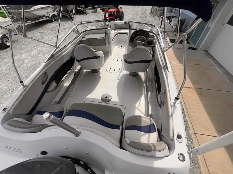 Slide: The Image of 2000 Four Winns 180 Horizon boat interior with seating and steering wheel, parked on gravel. - 4