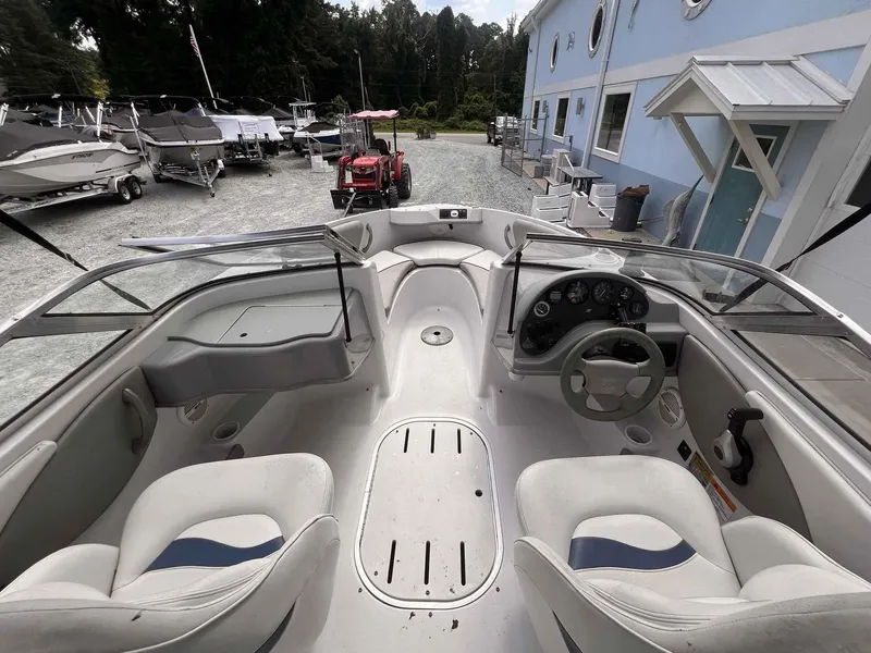 Slide: The Image of 2000 Four Winns 180 Horizon boat interior with steering wheel and seating, parked near other boats. - 5