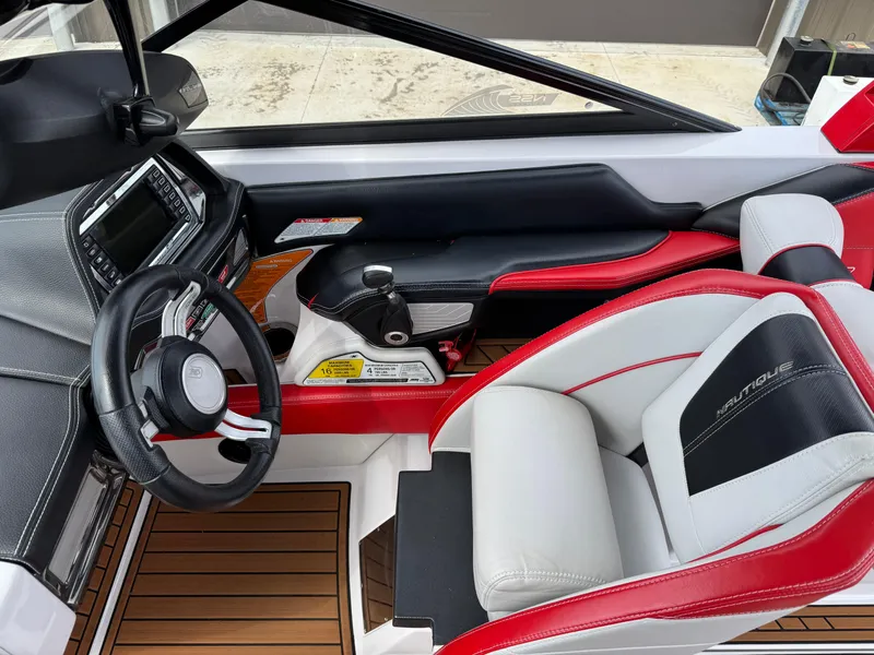 Slide: The Image of 2014 Correct Craft G23 boat interior with red and white seating, steering wheel, and dashboard controls. - 10