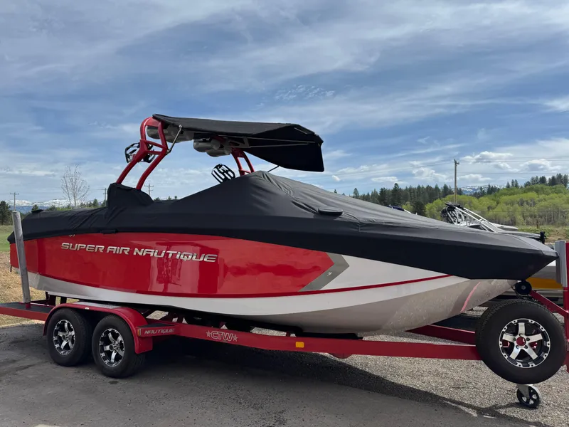 Slide: The Image of 2014 Correct Craft G23 boat covered on trailer, red and black design, outdoors. - 7