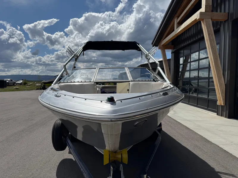 Slide: The Image of 2006 Four Winns Horizon boat on trailer, parked near a modern building under a cloudy sky. - 7