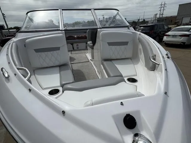 Slide: The Image of 2019 Regal 1900 ES boat with white seating and cup holders, parked outdoors. - 7