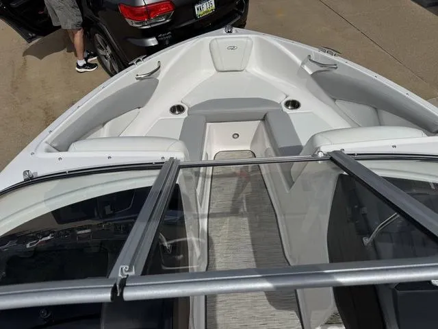 Slide: The Image of 2019 Regal 1900 ES boat interior with seating and cup holders, parked near a black vehicle. - 8